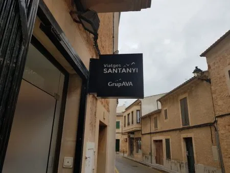 Rótulo bandera de una agencia de viajes colgado en una fachada