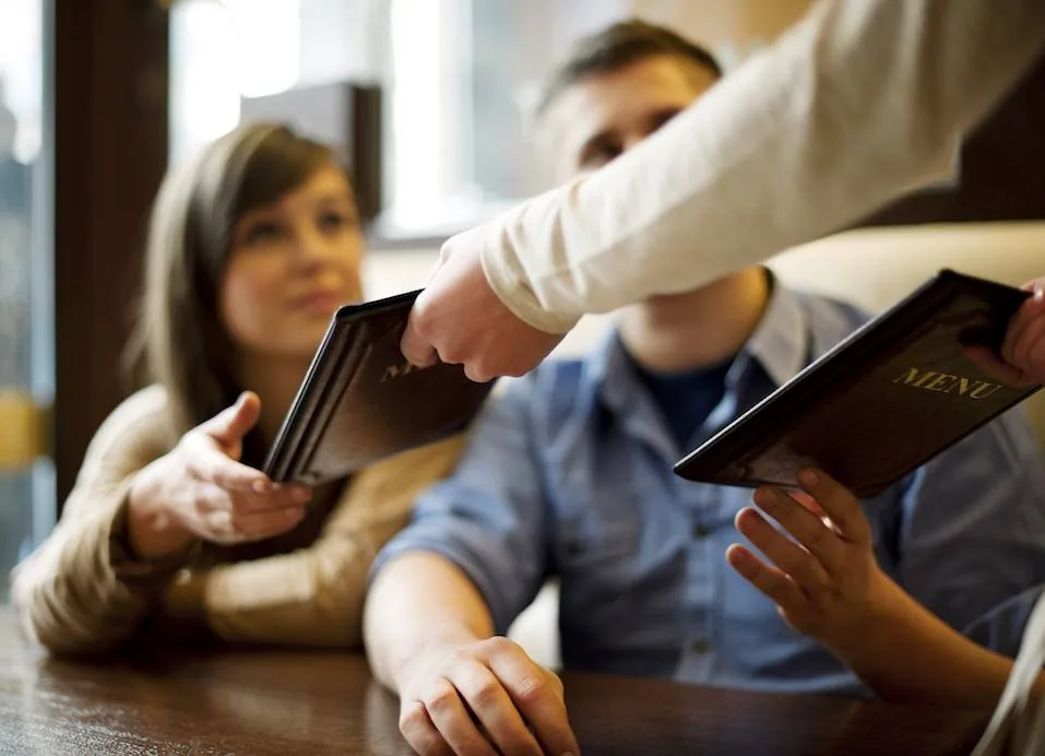 Clientes consultando una carta de restaurante impresa