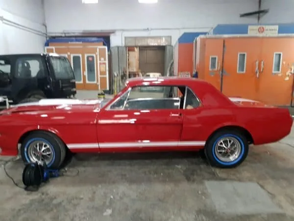 Coche clásico rojo en el taller con llantas azules